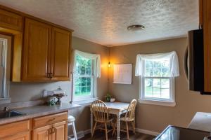 cocina con mesa y 2 ventanas en Rocky Retreat, en Warsaw