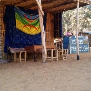 Tienda con mesa, sillas y cartel en Obira Oasis Merzouga Camp, en Merzouga