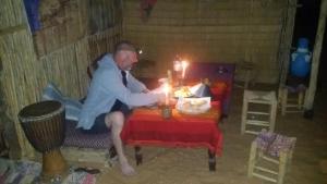 un hombre sentado en una mesa con velas encendidas en Obira Oasis Merzouga Camp, en Merzouga