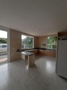 a large kitchen with a table and a refrigerator at Quinta la Rivera Villavicencio in Villavicencio