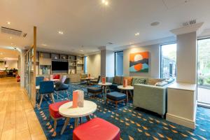 a hotel lobby with tables and chairs at Holiday Inn - Glasgow Airport by IHG in Paisley