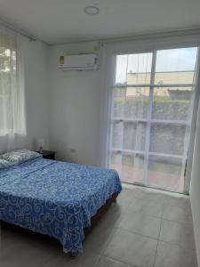 um quarto com uma cama e uma grande janela em Quinta la Rivera Villavicencio em Villavicencio