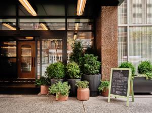 um sinal em frente a um edifício com vasos de plantas em Romer Hell's Kitchen em Nova York