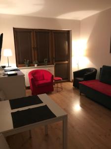 ein Wohnzimmer mit einem roten Sofa und Stühlen in der Unterkunft Apartament Józefa in Toruń