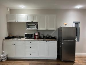 cocina con armarios blancos y nevera de acero inoxidable en Entire Guest suite & Vacation home in Whitehorse en Whitehorse