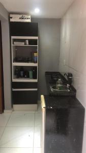 uma pequena cozinha com um lavatório e um frigorífico aberto em Kitnet dos Alves em Maricá