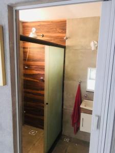 a bathroom with a door to a shower with a sink at Kitnet dos Alves in Maricá