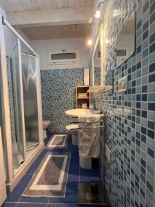 ein blau gefliestes Badezimmer mit Waschbecken und Toilette in der Unterkunft La casa tra gli alberi e il cottage in Fiskardo