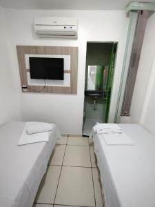 a small room with two beds and a tv at Hotel Vitoria Iracema in Juazeiro do Norte