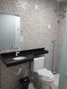 a bathroom with a toilet and a sink and a mirror at Hotel Vitoria Iracema in Juazeiro do Norte