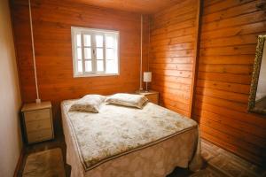 a bedroom with a bed in a wooden room at Pousada recanto entre Rios Casa Vó Silvina in Urubici