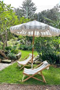 two lounge chairs under an umbrella in the grass at Avalon Beach Cottage- The Islander in Avalon