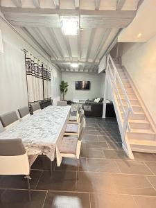 a dining room with a table and chairs and stairs at Maison Cosy , parking gratuit , 5 min aux Auxerre in Auxerre