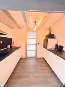 a large kitchen with white cabinets and a door at Maison Cosy , parking gratuit , 5 min aux Auxerre in Auxerre