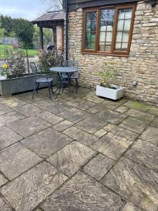 a patio with a table and chairs and a building at One bedroom Countryside Annexe in Boars Hill