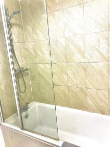 een douche met een glazen deur en een bad bij Las Olas ~ Entire home with hot tub in Tythegston