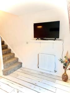 een trap met een flatscreen-tv aan een muur bij Las Olas ~ Entire home with hot tub in Tythegston
