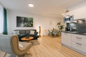 eine Küche und ein Wohnzimmer mit einem Sofa und einem Tisch in der Unterkunft Modernes 2-Zimmer Themen-Apartment "Frankenwald" im Zentrum in Bayreuth