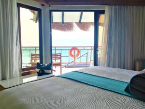 a bedroom with a bed and a view of the ocean at Palafitos Overwater Bungalows El Dorado Maroma - Adults Only in Playa del Carmen