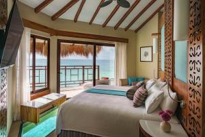 a bedroom with a bed and a view of the ocean at Palafitos Overwater Bungalows El Dorado Maroma - Adults Only in Playa del Carmen