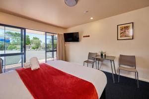 a bedroom with a bed and a desk and a television at Mediterranean Motel Kaikoura in Kaikoura