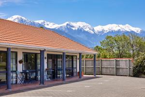 a building with a table and chairs in front of mountains at Mediterranean Motel Kaikoura in Kaikoura