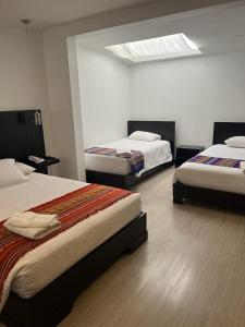 a bedroom with two beds and a skylight at Hostal Entre Ríos in Cuenca