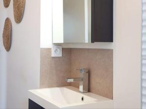 ein Badezimmer mit einem weißen Waschbecken und einem Spiegel in der Unterkunft Le Cosy Paradis par Madame Conciergerie in Bruz