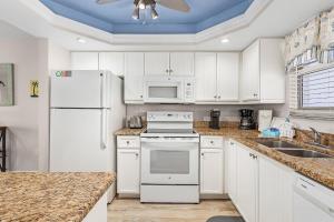a kitchen with white appliances and a blue ceiling at Fantastic Gulf Front Condo on the North end of the Island condo in Fort Myers Beach +22 photos