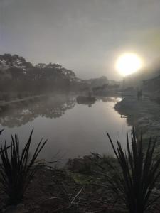 a misty river with the sun in the background at Pousada Nó de Pinho in Urubici