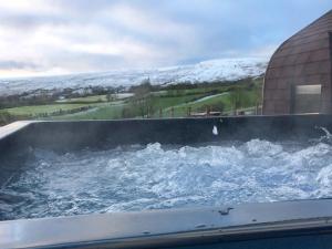 uma grande banheira cheia de água ao lado de um edifício em Carntogher Cabins em Derry Londonderry