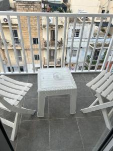 a white table and two chairs on a balcony at Sunquest court in St Paul's Bay