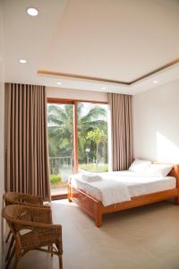 um quarto com uma cama, uma cadeira e uma janela em Sông Mê Home em Vinh Long