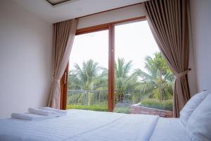 ein Schlafzimmer mit einem Bett und einem großen Fenster in der Unterkunft Sông Mê Home in Vĩnh Long