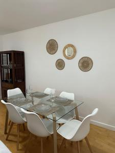 comedor con mesa de cristal y sillas blancas en Apartamento Los Lances, en Ronda