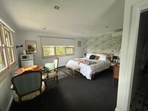 a bedroom with a bed and a desk and a table at Rainy Hill Retreat - The Cottage in Cockatoo