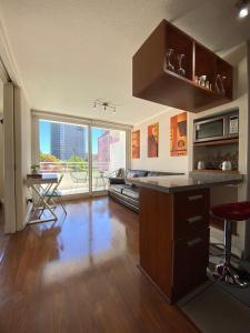 a kitchen with a counter and a table and a large window at Hermoso departamento a pasos de UdeC in Concepción