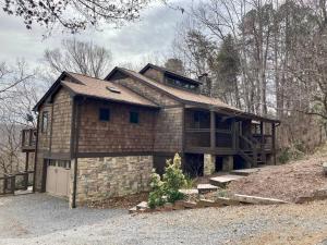 a large brick house with a garage on a hill at Entire 3 Bedroom Home in Rumbling Bald Resort in Lake Lure