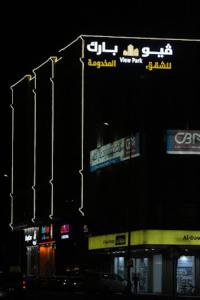 un edificio con señales a un lado por la noche en فيوبارك للشقق الفندقية, en Al Hofuf