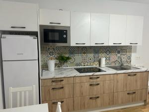 cocina con armarios blancos y nevera blanca en Welcome to casa Coralia, 