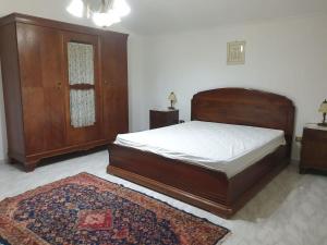 ein Schlafzimmer mit einem großen Holzbett und einem Teppich in der Unterkunft Appartamento L'Oleandro B&B in Faggiano