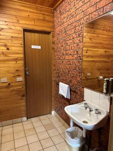 a bathroom with a sink and a brick wall at Merrijig Motor Inn in Merrijig