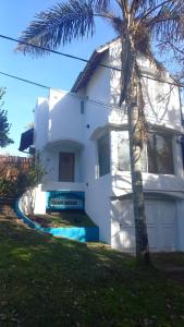 a white house with a palm tree in front of it at El lugar in Villa Gesell