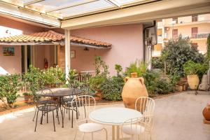 un patio al aire libre con mesas, sillas y un jarrón en B&B Cumpari Turiddu, en Siracusa