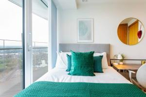 ein Schlafzimmer mit einem Bett mit grünen Kissen und einem Fenster in der Unterkunft Panoramic balcony luxury condo in London