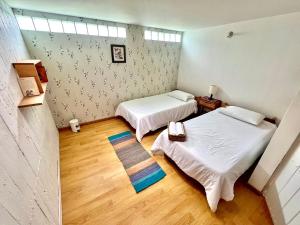 two beds in a small room with wooden floors at B&B - Trekking y Senderismo in Choachí