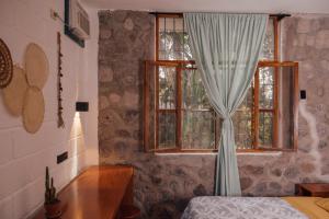 1 dormitorio con ventana con cortina y mesa en Hostal Pimampiro, en Puerto Baquerizo Moreno