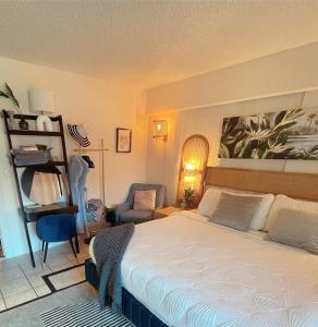 a bedroom with a large bed and a chair at Seashore Waikiki studio 1 block from a beach No Resort Fees in Honolulu