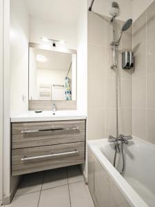 uma casa de banho com um lavatório, uma banheira e um espelho. em Maison de Charme - parking gratuit près de Paris & métro em Villejuif