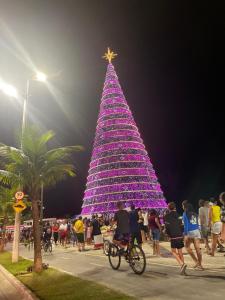 un gran árbol de Navidad con gente caminando alrededor de él en Kitnet perto da praia, en Praia Grande